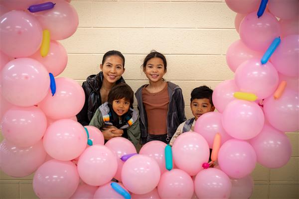 family smiling in the whole of pink donut